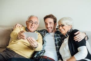 Adult son taking a selfie with his mother and father, highlighting the importance of staying connected when caring for aging parents.