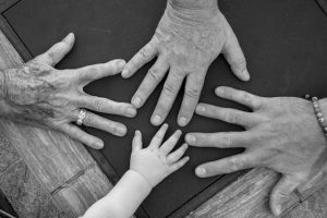 Four generations of hands on a table, illustrating giving while living across a family.